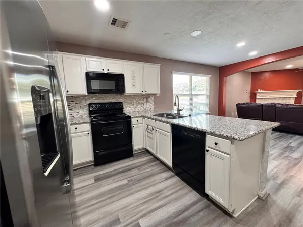 a kitchen with stainless steel appliances granite countertop a refrigerator a sink a stove a microwave a counter space and cabinets