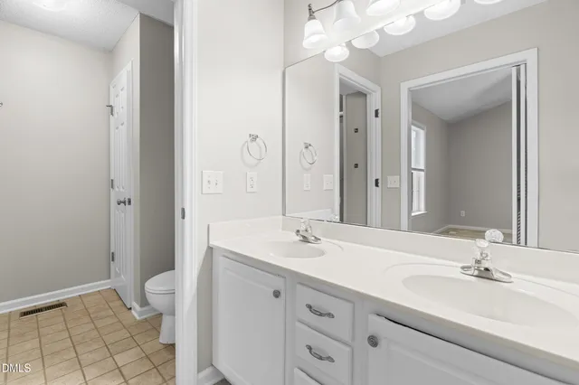 a bathroom with a double vanity sink mirror and toilet