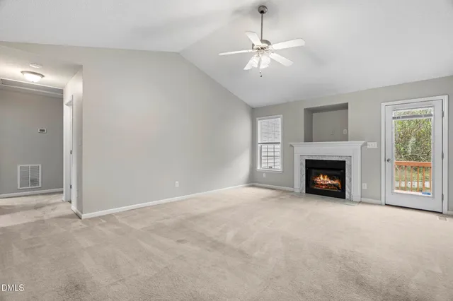an empty room with fireplace fan and windows