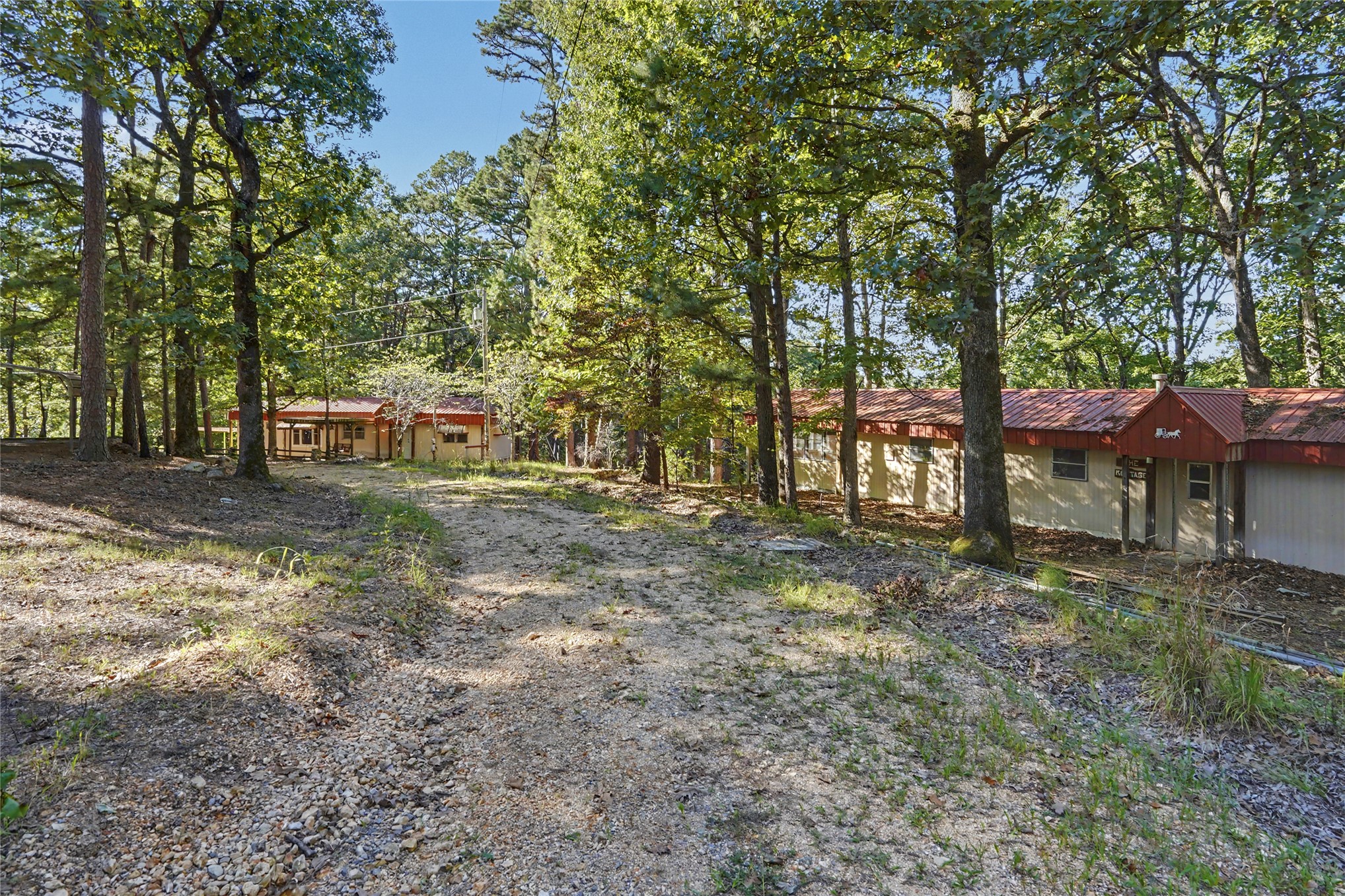 46420 South 590 Road Jay, OK 74346 - Photo 50 of 63 Gravel drive leading to a property with multiple structures, each featuring a red corrugated metal roof and light-colored siding