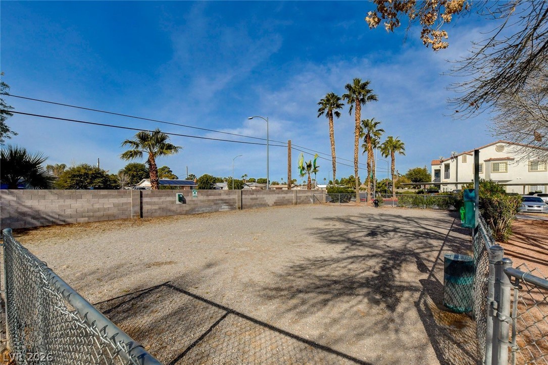 3318 North Decatur Boulevard, Unit 2072 Las Vegas, NV 89130 - Photo 43 of 50 A spacious, open community space for recreation, bordered by a concrete block wall and palm trees.