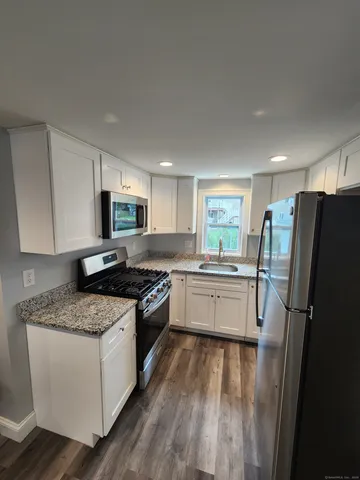 a kitchen with granite countertop a refrigerator stove and sink