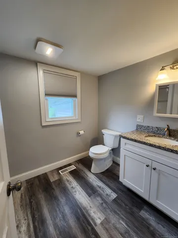 a bathroom with a granite countertop toilet and a sink