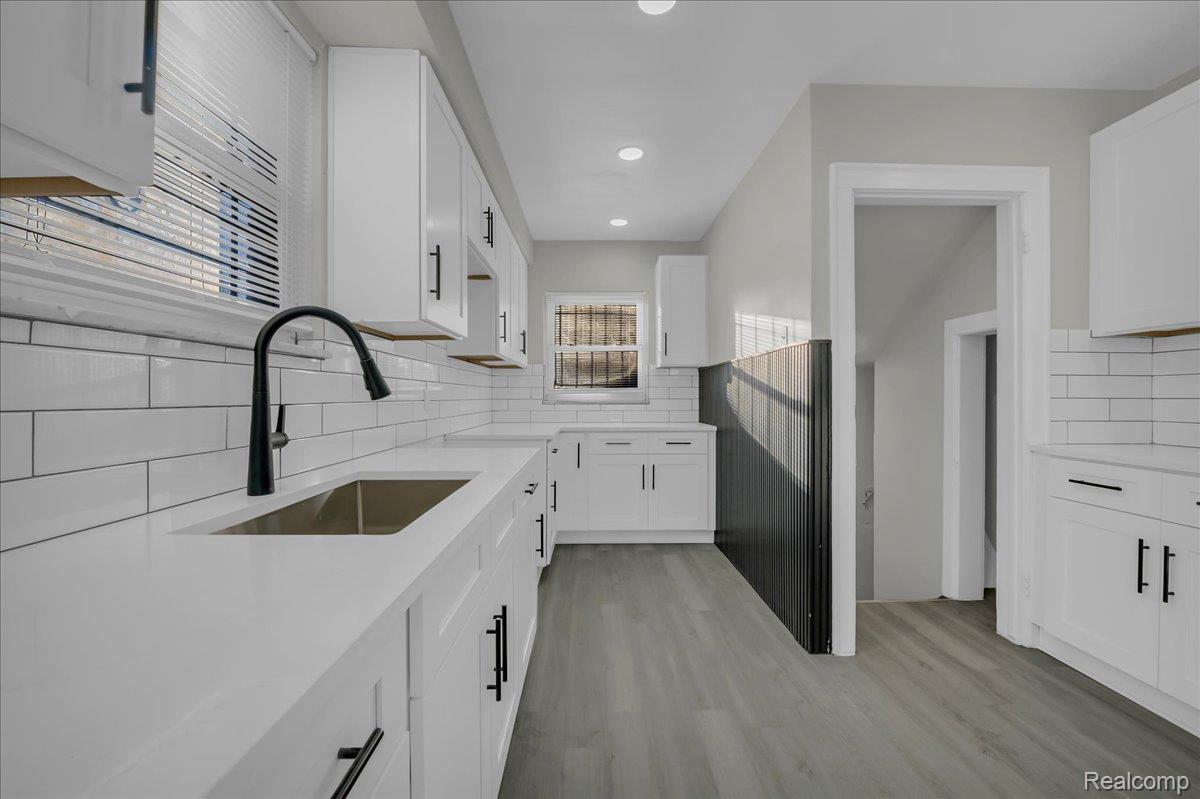 16717 Fielding Street Detroit, MI 48219 - Photo 14 of 46 Kitchen featuring light wood-style floors, white cabinets, backsplash, light stone countertops, and recessed lighting