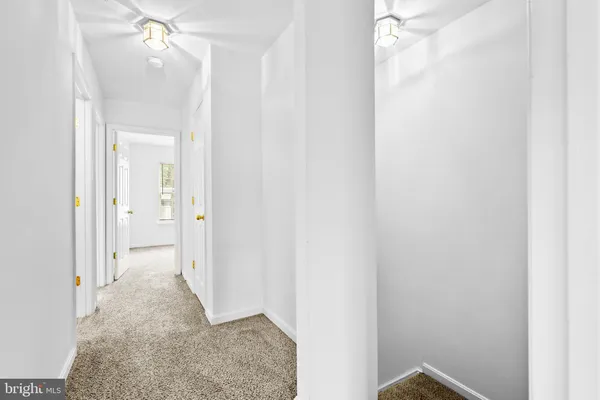 a view of a hallway with a chandelier fan and closet area