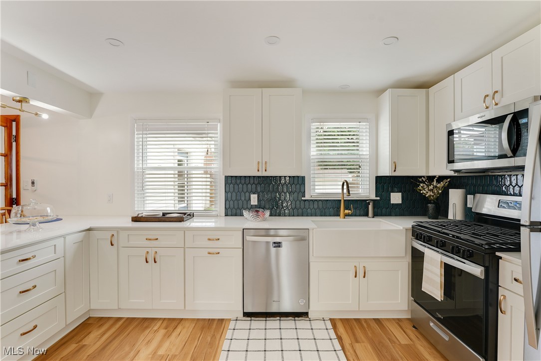 3841 Bethany Road Cleveland, OH 44118 - Photo 2 of 9 Kitchen with appliances with stainless steel finishes, a sink, light wood finished floors, white cabinets, and light countertops
