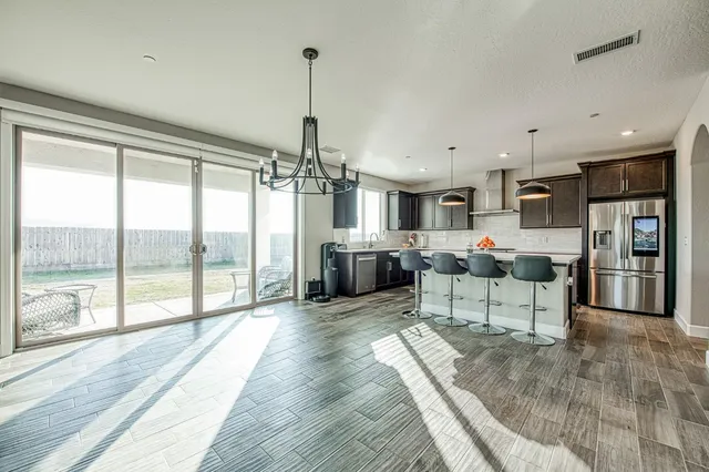 a living room with stainless steel appliances kitchen island granite countertop a refrigerator a stove top oven a sink dishwasher and a fireplace