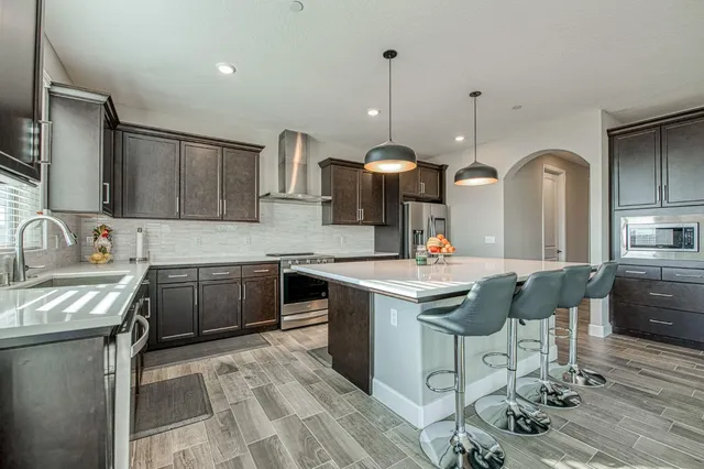 a kitchen with stainless steel appliances granite countertop a sink a stove and a wooden floors