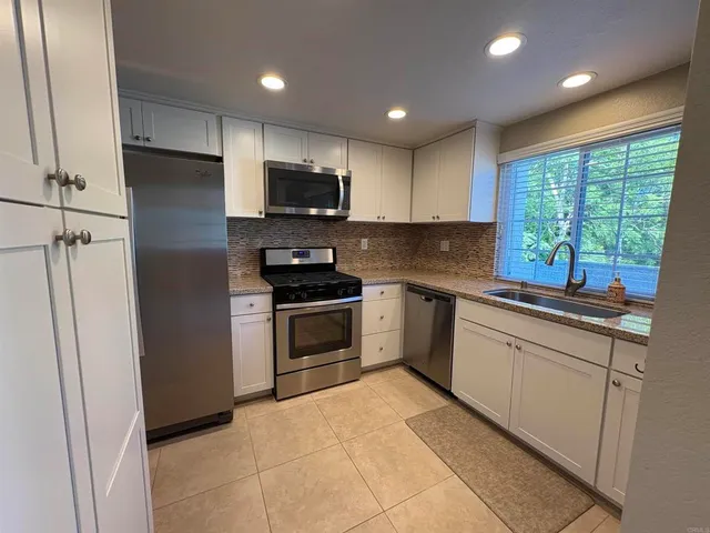 a kitchen with a sink a counter top space stainless steel appliances and a window