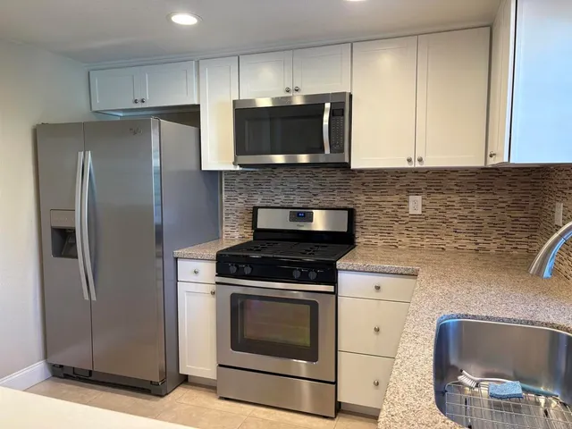 a kitchen with stainless steel appliances granite countertop a stove microwave and refrigerator