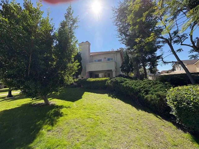 a view of a white house with a yard next to a road