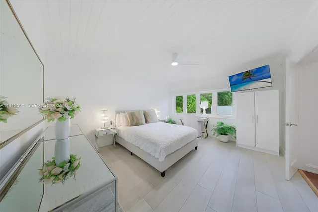a spacious bedroom with a bed table flowerpot and a potted plant