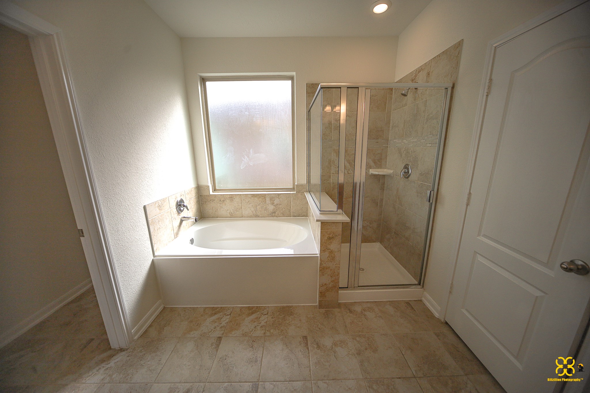 5820 Bluebonnet Lane Rosenberg, TX 77469 - Photo 27 of 43 This Master Bathroom features a spacious layout with a large soaking tub next to a glass-enclosed shower. The room is well-lit with a frosted window and has neutral tile flooring and walls for a clean, modern look.