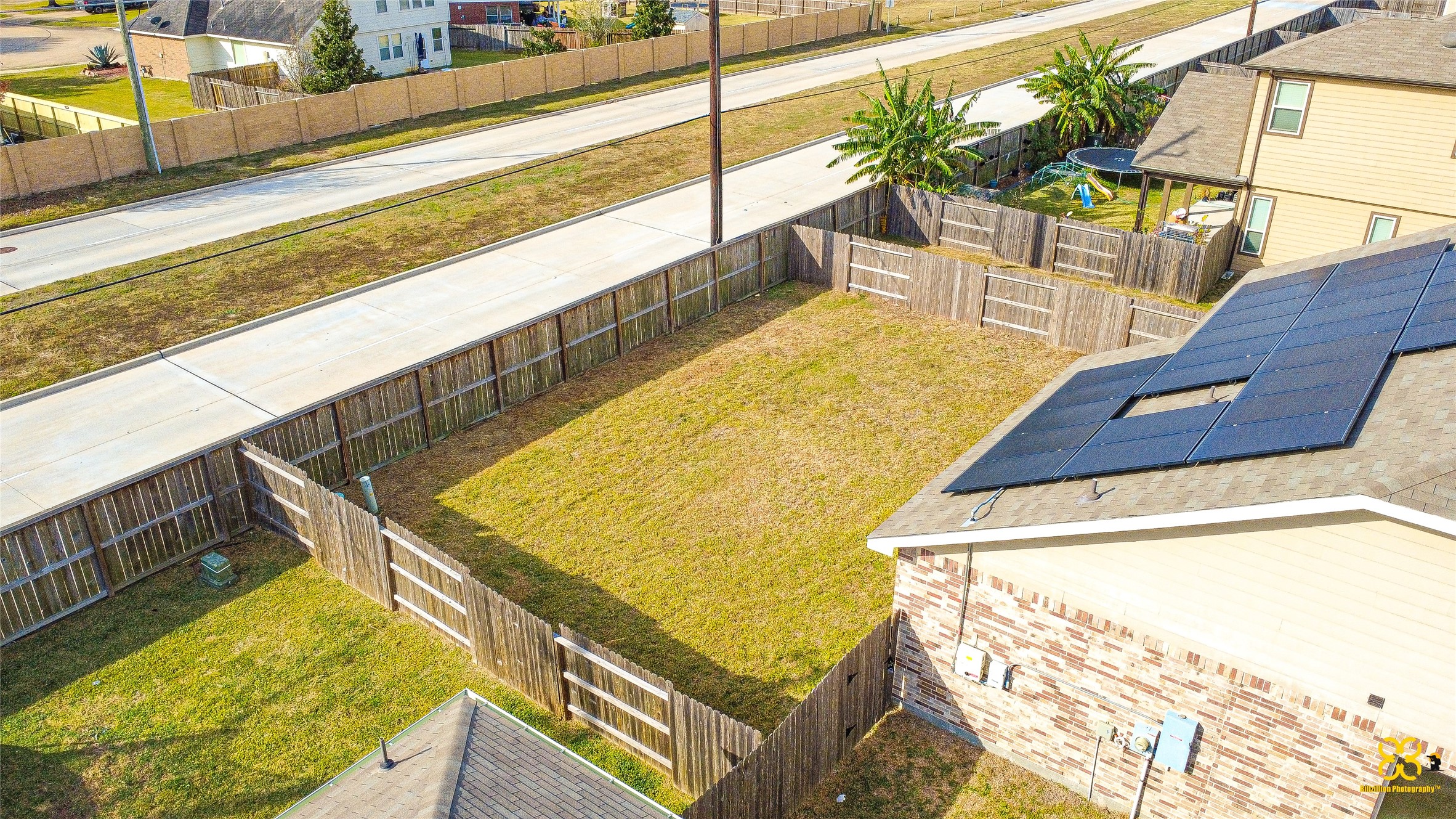 5820 Bluebonnet Lane Rosenberg, TX 77469 - Photo 7 of 43 Spacious backyard with wooden fencing, adjacent to a quiet street. The house features solar panels, offering energy efficiency. Ideal for outdoor activities and privacy.