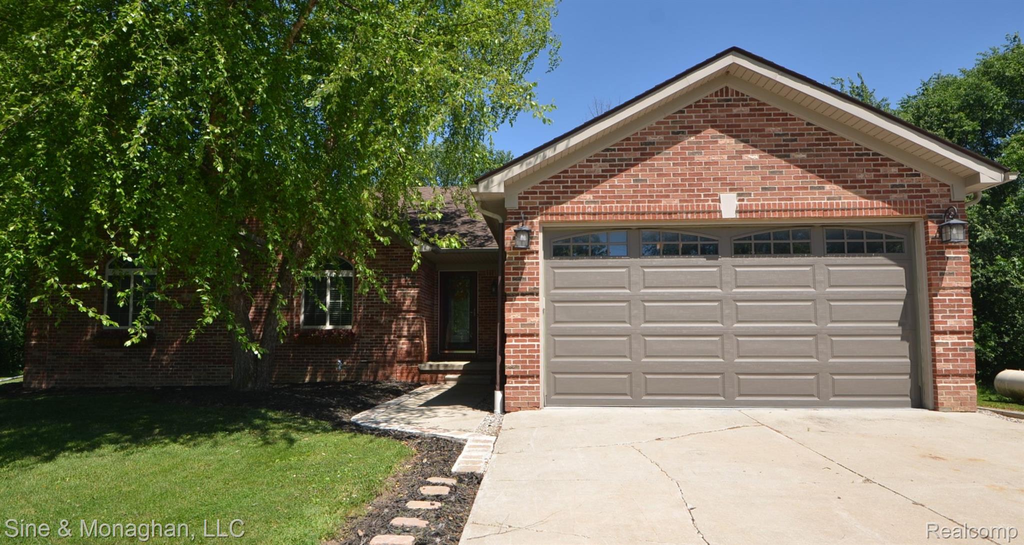 76152 Burman Road Richmond, MI 48062 - Photo 1 of 75 Brick exterior featuring a two-car garage with arched window panels, concrete driveway, and a stone-paver walkway leading to the front entry