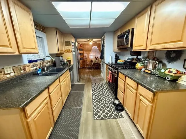 a kitchen with stainless steel appliances granite countertop a sink a stove and a wooden cabinets