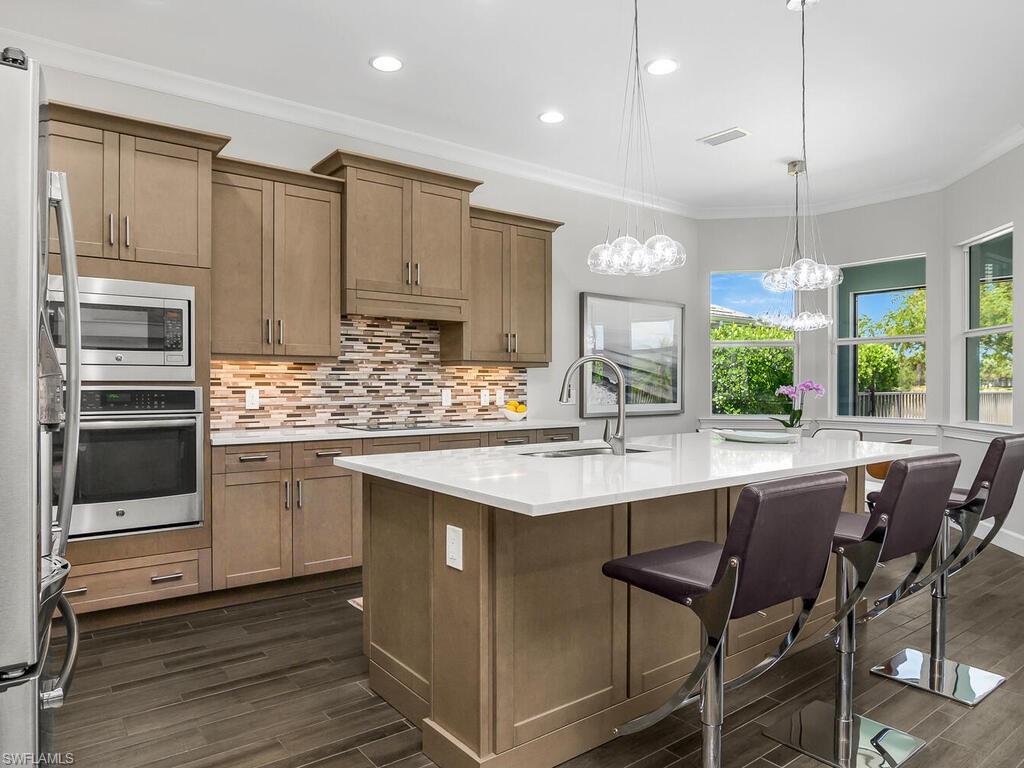 6478 Warwick Avenue Naples, FL 34113 - Photo 5 of 47 a kitchen with kitchen island granite countertop a sink and white cabinets