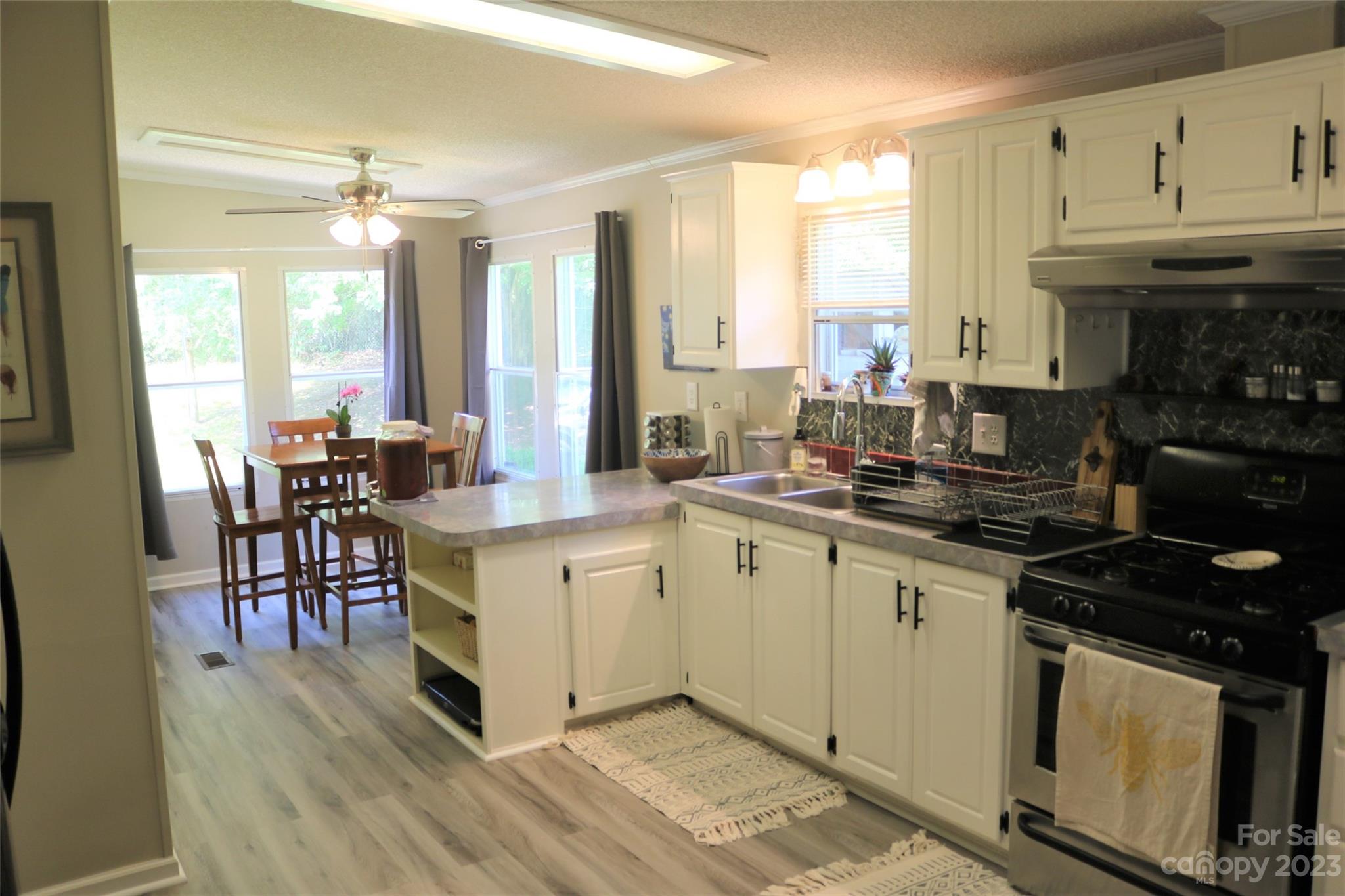 2919 Grassy Knob Road Mill Spring, NC 28756 - Photo 10 of 29 a kitchen with stainless steel appliances granite countertop a stove top oven a sink dishwasher a dining table and chairs with wooden floor