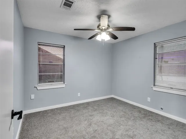 an empty room with a window and a fan