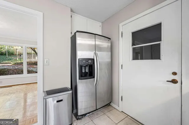 a view of a refrigerator in kitchen and an empty room