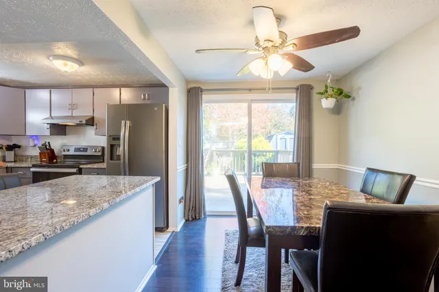 a kitchen with stainless steel appliances granite countertop a refrigerator a sink a stove a dining table and chairs