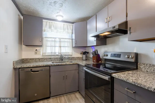 a kitchen with granite countertop a stove cabinets and refrigerator