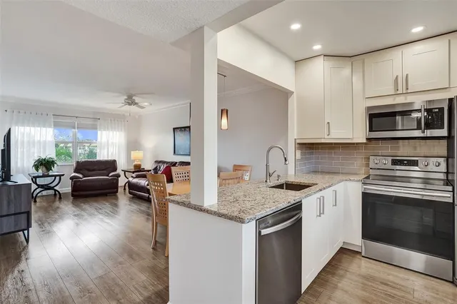 a kitchen with a sink dishwasher a stove and a microwave oven with wooden floor