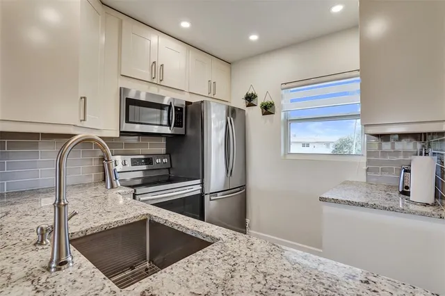 a kitchen with stainless steel appliances kitchen island granite countertop a refrigerator sink and microwave