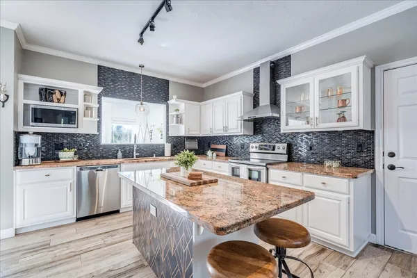 a kitchen with stainless steel appliances granite countertop a stove top oven a sink a counter space and cabinets