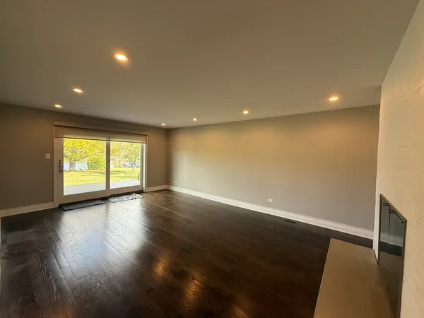 an empty room with wooden floor and windows with curtains