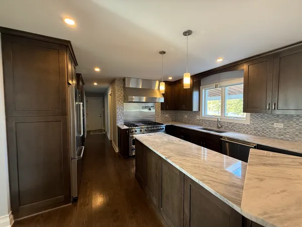 a kitchen with stainless steel appliances granite countertop a refrigerator a sink and a stove