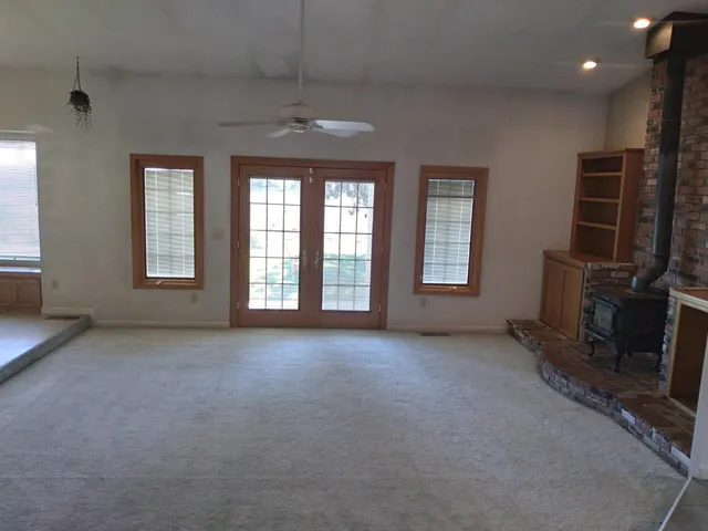 an empty room with windows and fireplace
