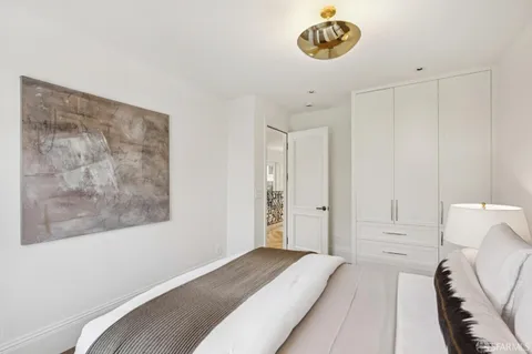 a living room with lots of white furniture and a painting on the wall