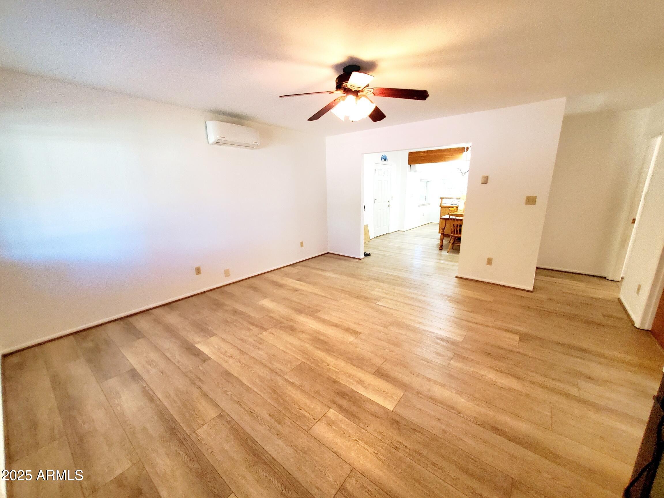 8449 Elk Road Pine, AZ 85544 - Photo 8 of 24 an empty room with wooden floor ceiling fan and windows