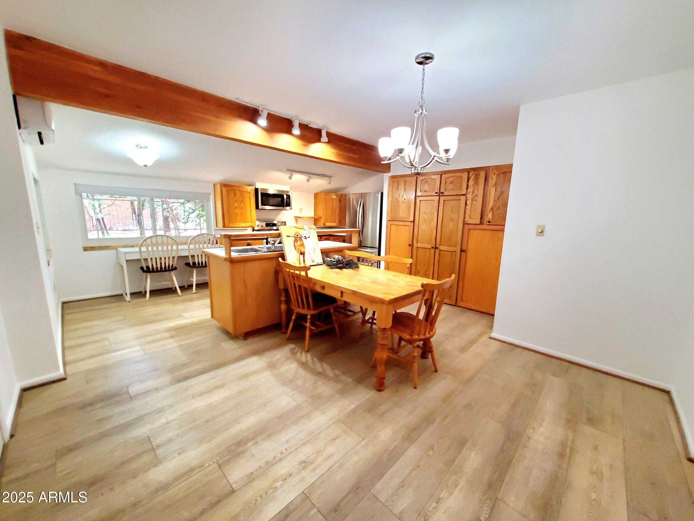 8449 Elk Road Pine, AZ 85544 - Photo 10 of 24 a dining room with wooden floor a chandelier a wooden table and chairs