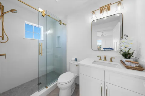 a bathroom with a shower sink vanity mirror and toilet
