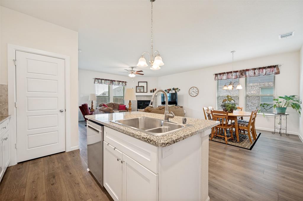 413 Wiggins Way Van Alstyne, TX 75495 - Photo 6 of 25 Kitchen island featuring a double basin sink, stainless steel faucet, and granite countertop