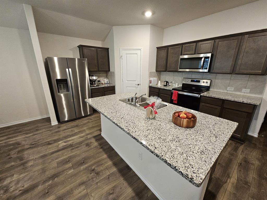 a kitchen with stainless steel appliances granite countertop a sink dishwasher microwave stove and refrigerator