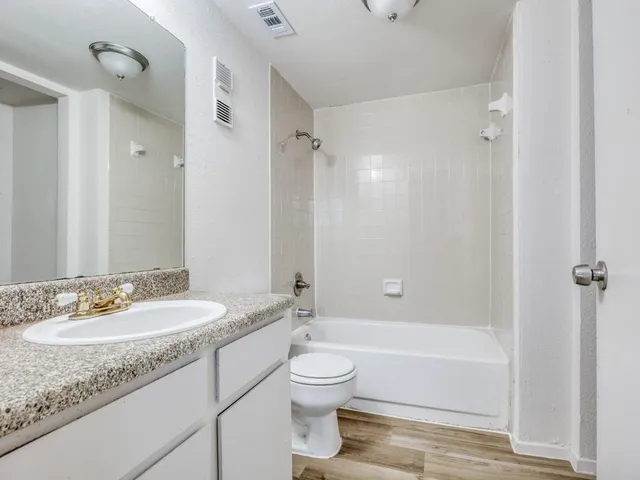 a bathroom with a granite countertop sink toilet a large mirror a bathtub and shower