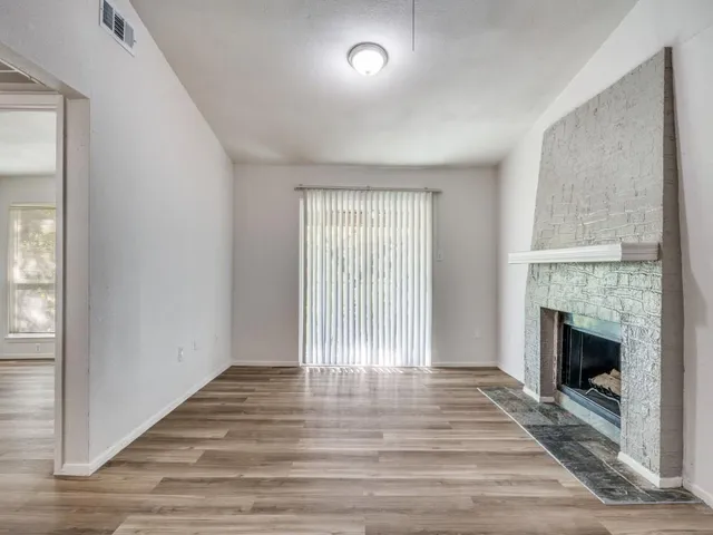 a view of empty room with wooden floor and fireplace