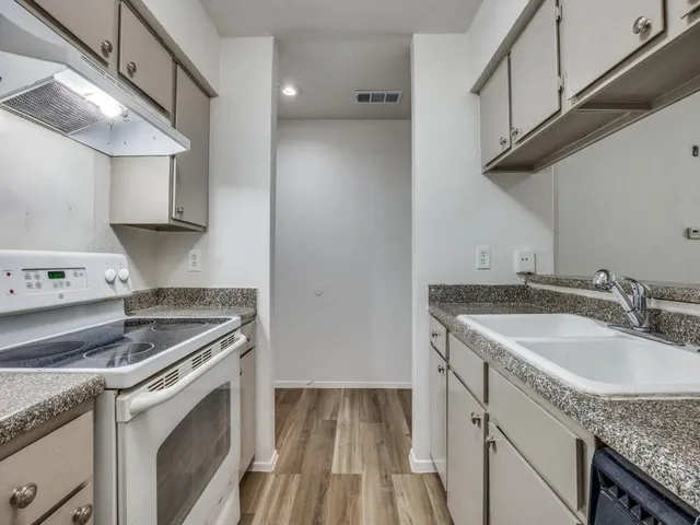 a kitchen with granite countertop a sink stove and cabinets