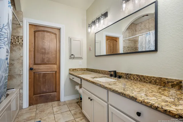 a bathroom with a granite countertop sink and a mirror
