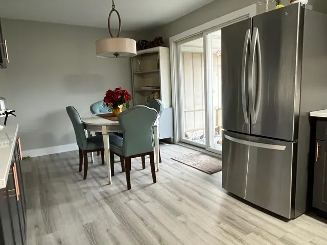 a kitchen with stainless steel appliances granite countertop a refrigerator dining table and chairs
