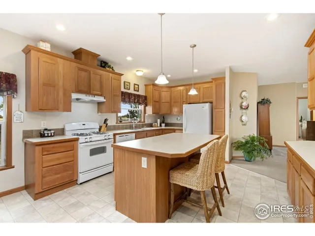 a kitchen with stainless steel appliances kitchen island granite countertop a table chairs sink and cabinets