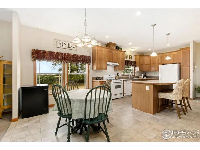 a dining room with furniture a floor to ceiling window and kitchen view