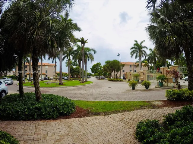 a front view of multi story residential apartment building with yard and green space