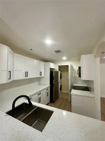 a kitchen with granite countertop a refrigerator and a sink