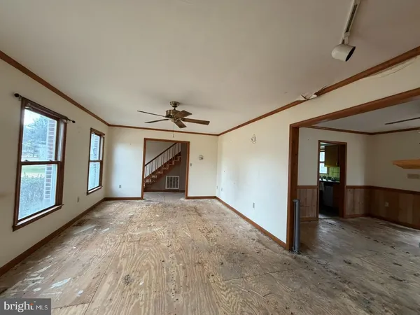 an empty room with chandelier fan and windows