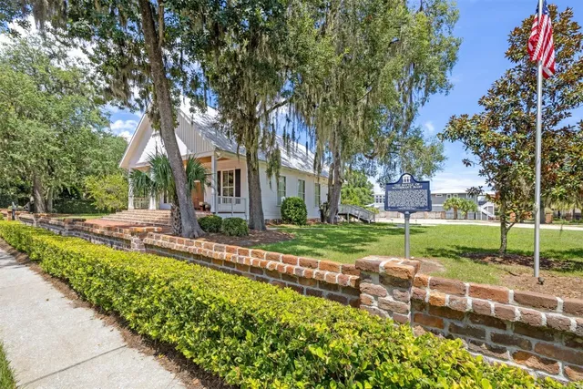 a front view of a house with a garden and trees
