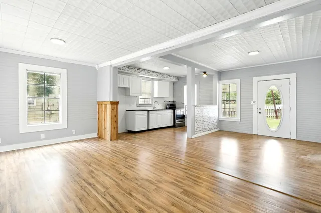 a view of a electric appliances in kitchen and empty room with wooden floor
